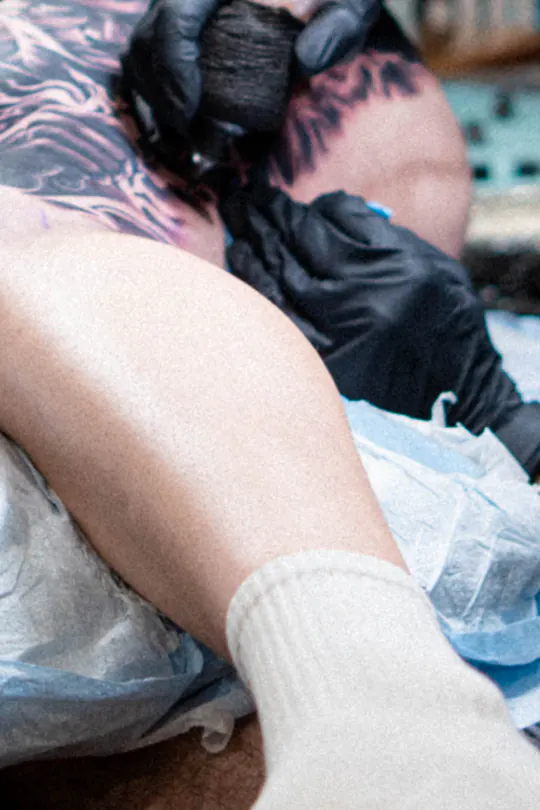 Close-up of a tattoo artist’s gloved hands at work.